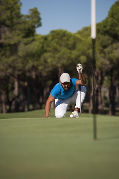 jugador de golf apuntando tiro con club en curso en hermoso día soleado