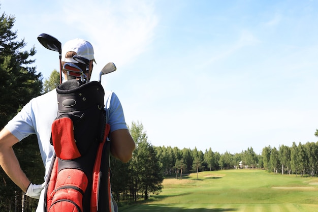 Jugador de golf caminando y llevando una bolsa en el campo durante el juego de golf de verano.