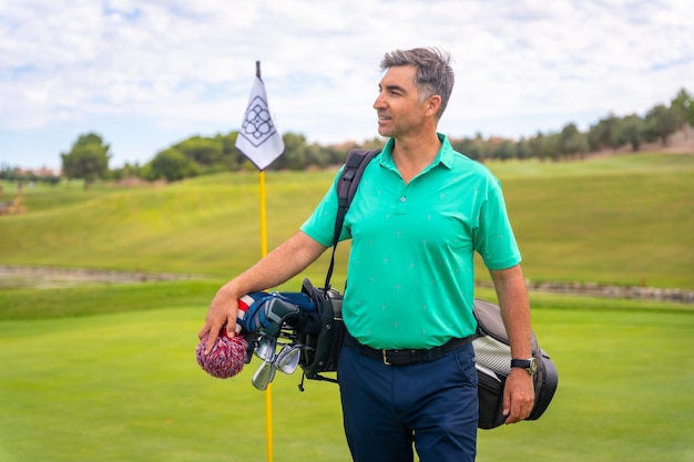 Un jugador de golf caucásico profesional en un campo de golf junto a la bandera en el green