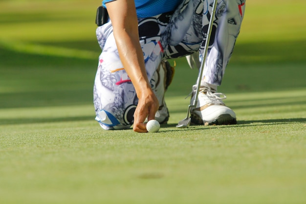 Jugador de golf en cuclillas para poner la bola