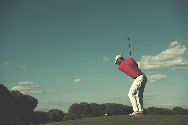 jugador de golf golpeando tiro con conductor en curso en un hermoso día soleado