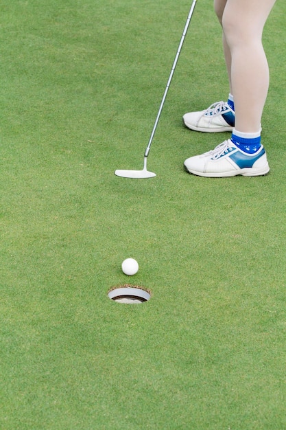 Jugador de golf de mujer poniendo en el green