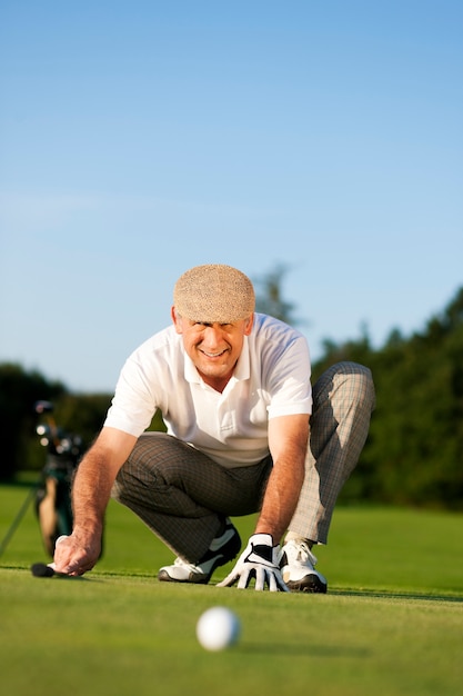 Jugador de golf Senior mirando una pelota