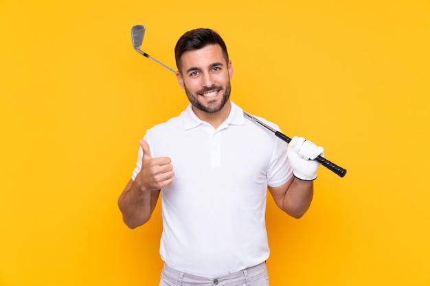 Jugador de golfista hombre sobre pared amarilla aislada con pulgares arriba porque algo bueno ha sucedido