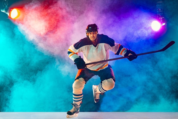 Jugador de hockey masculino líder en la cancha de hielo y fondo de color neón oscuro con linternas