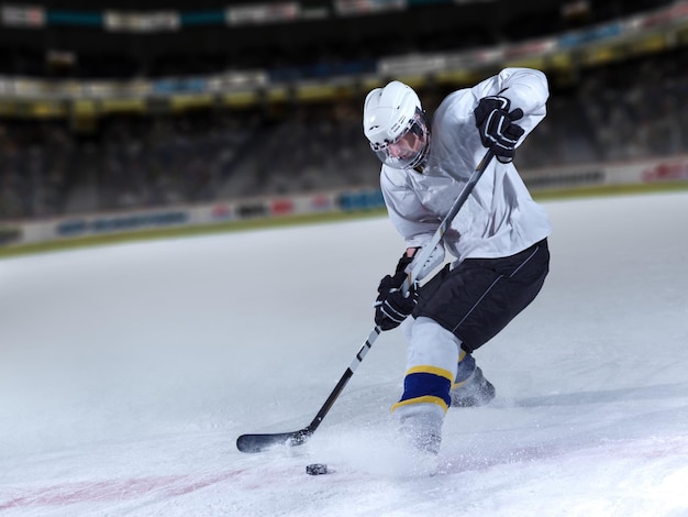 Foto jugador de hockey sobre hielo en acción pateando con palo