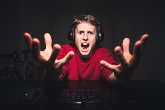 jugador jugando juegos en la noche en una computadora y emocional mirando a la cámara