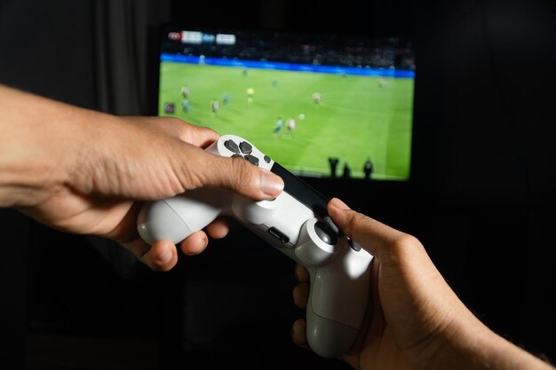 Jugador jugando un videojuego de fútbol en una consola con un controlador inalámbrico