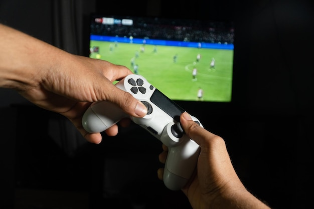 Jugador jugando a un videojuego de fútbol con un controlador inalámbrico