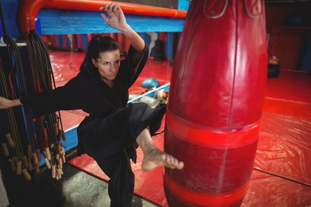 Jugador de karate femenino practicando boxeo con saco de boxeo