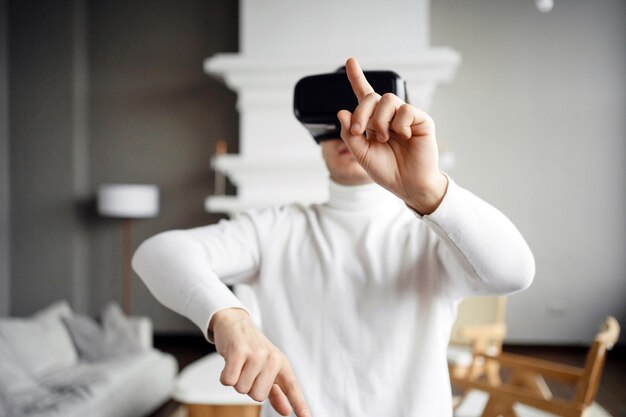 Un jugador masculino usa gafas de realidad virtual, presiona botones y juega un videojuego en un apartamento