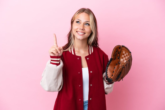 Jugador mujer rusa con guante de béisbol aislado sobre fondo rosa apuntando hacia una gran idea