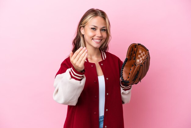 Jugador mujer rusa con guante de béisbol aislado sobre fondo rosa invitando a venir con la mano Feliz de que hayas venido