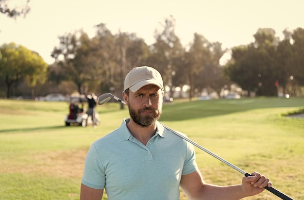 Jugador de oro de hombre en gorra con palo de golf en golf de hierba verde de verano