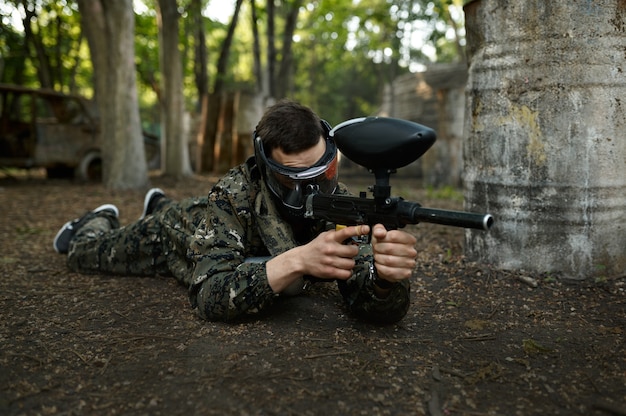 Jugador de paintball dispara acostado en el suelo