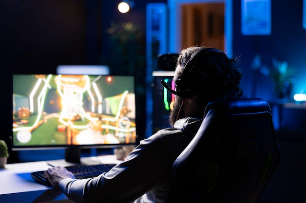 Jugador profesional compitiendo en un intenso videojuego multijugador en línea después de llegar a casa