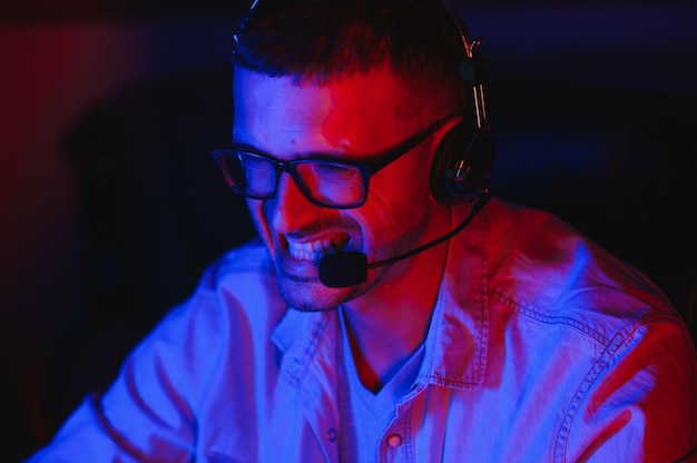 Jugador profesional juega videojuegos en su computadora. Está participando en el Torneo de Juegos Cibernéticos en Línea o en el Café Internet. Lleva gafas y habla por micrófono.
