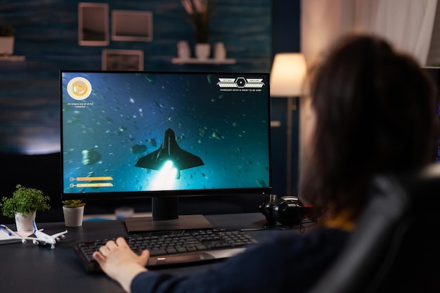 Jugador que usa el teclado para jugar videojuegos digitales. Mujer jugando juegos en línea con consola de control en la computadora, haciendo una actividad divertida. Jugador que usa equipos de juego modernos en el ciberespacio.