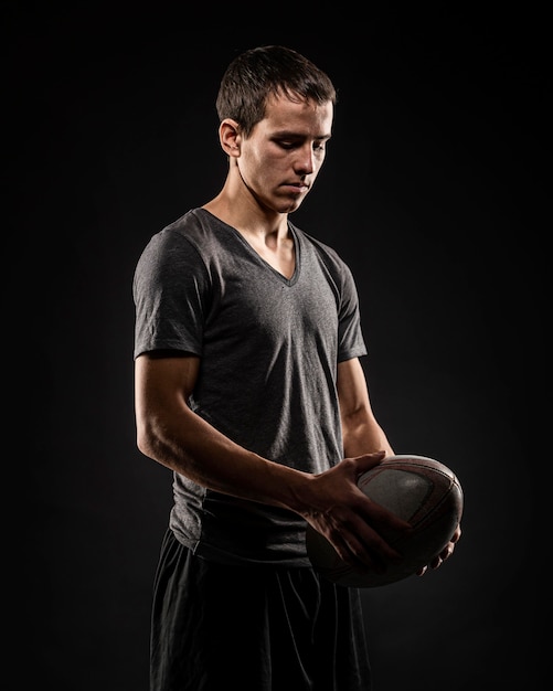 Foto jugador de rugby masculino guapo sosteniendo la bola