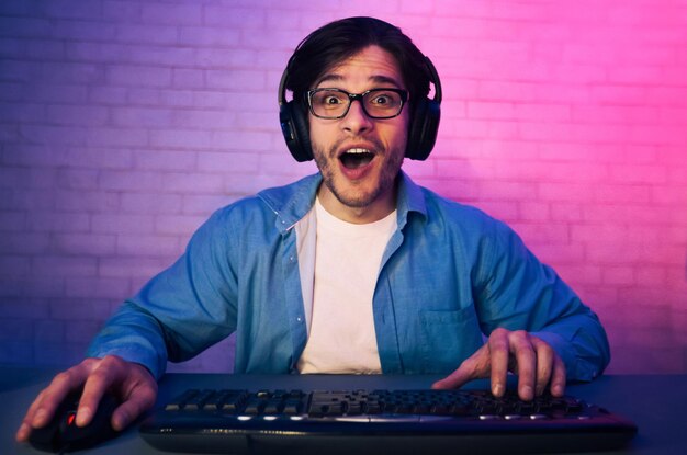Jugador sorprendido con auriculares y gafas jugando a videojuegos