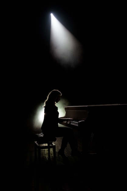 Jugador de teclados en el escenario durante el concierto, luz de fondo