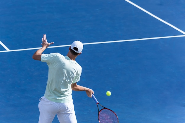 Jugador de tenis en cancha dura azul