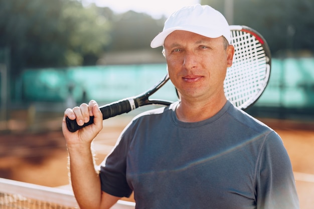 Jugador de tenis de hombre de mediana edad con pie de raqueta en la cancha cerca de la red