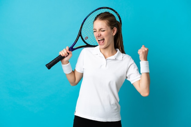 Jugador de tenis joven aislado en azul celebrando una victoria