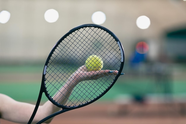 Jugador de tenis manos femeninas jugando entrenamiento con raqueta y pelota en la cancha