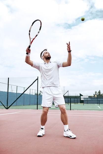 Jugador de tenis profesional está haciendo una patada de tenis en una cancha de tenis en un soleado