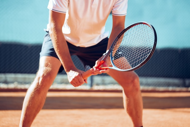 Jugador de tenis profesional de pie en posición de listo en la cancha de tenis