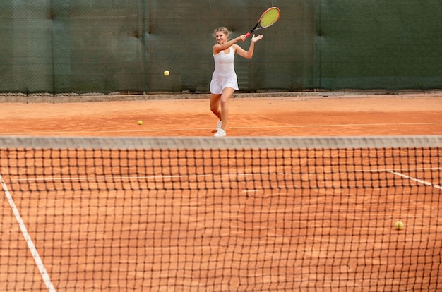 Jugador de tenis en ropa deportiva blanca preparándose para servir entrenamiento de pelota de tenis antes del partido