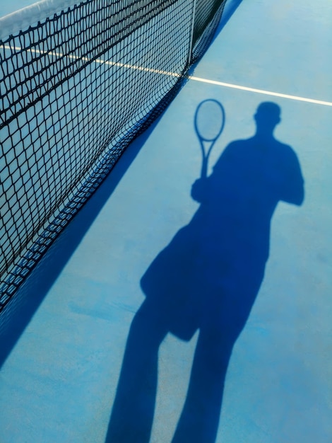 Jugador de tenis y sombra en una cancha de tenis Fondo de tenis