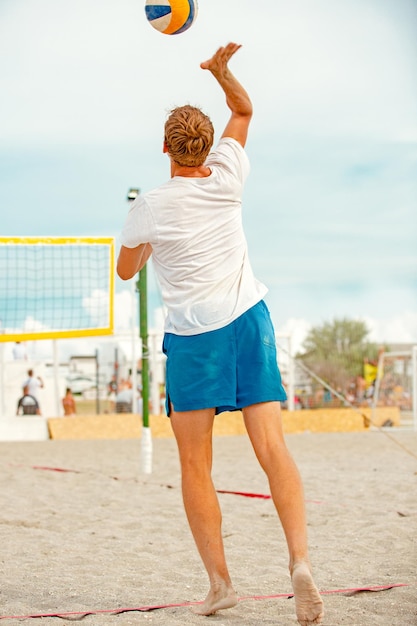 El jugador de voleibol de playa es un atleta masculino que se prepara para servir la pelota en la playa.