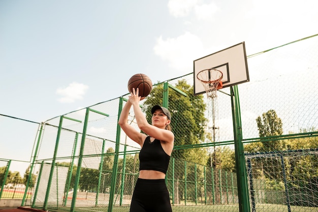 Jugadora de baloncesto atlética lanzando una pelota a la red