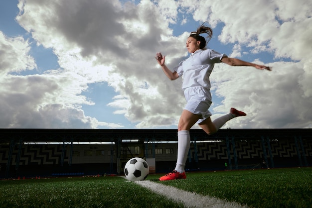 jugadora de fútbol deportiva con un balón de fútbol en el campo de fútbol el concepto de fútbol femenino profesional