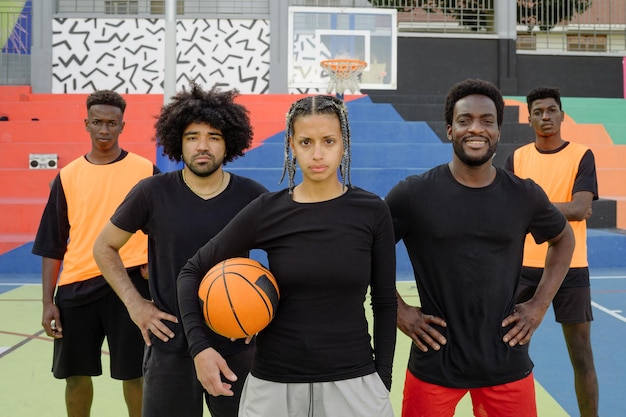 Foto jugadores confiados de pie en la cancha de baloncesto