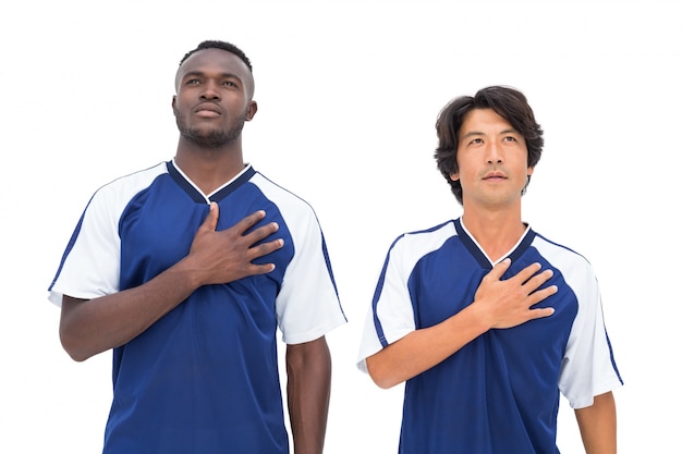 Jugadores de fútbol en azul escuchando el himno