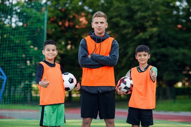 Jugadores de fútbol feliz de pie en el campo de fútbol con el entrenador