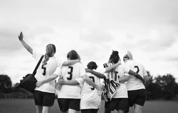 Jugadores de fútbol femenino acurrucados y caminando juntos