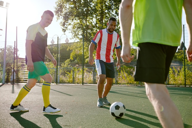 Foto jugadores de fútbol jugando a la pelota en el campo de fútbol callejero de la ciudad mejores amigos masculinos recreación activa y pasatiempo común