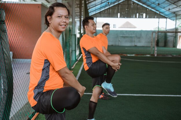 Los jugadores de fútbol sala sonríen mientras estiran las piernas antes del partido