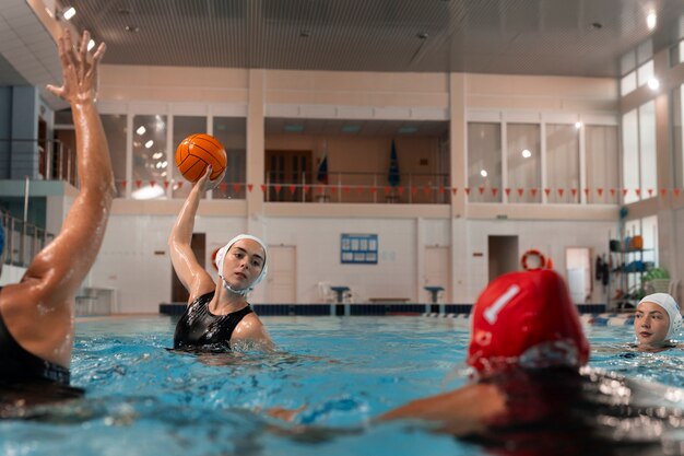 Foto jugadores de waterpolo en la piscina con equipo de natación.