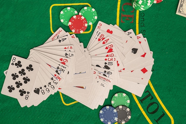 Jugando a las cartas de diferentes colores, fichas de colores esparcidas en la nueva mesa de póquer Concepto de póquer