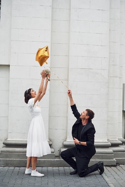 Jugando con globo de color dorado Hermosa novia con su prometida está celebrando la boda al aire libre