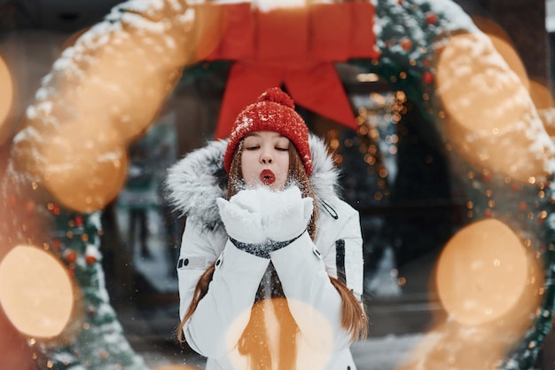 Jugando con nieve Mujer joven feliz de pie al aire libre y celebrando las fiestas navideñas