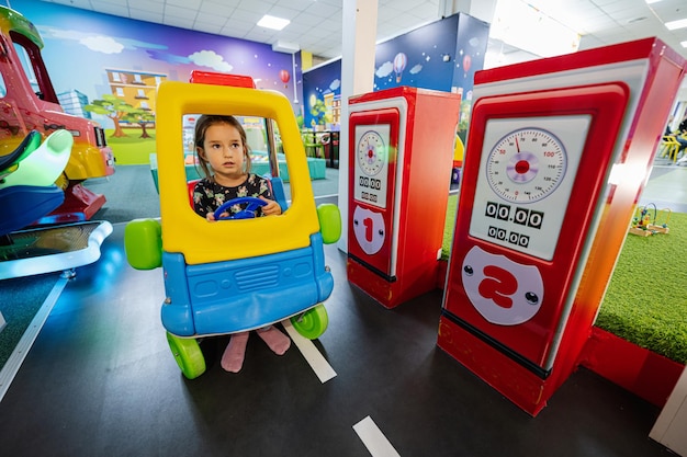 Jugando en el patio interior del centro de juegos niña en la gasolinera de coches de juguete