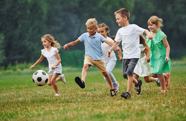Jugando a la pelota de fútbol juntos Los niños se divierten en el campo durante el día