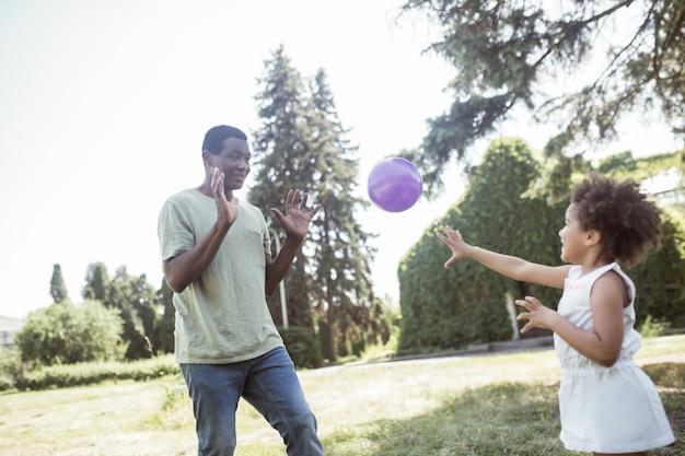 Jugando pelota. Papá y una linda niña jugando a la pelota en el parque