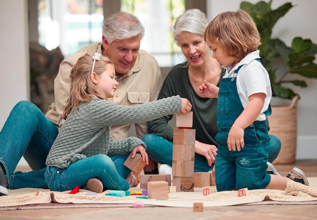 Jugar bloques de madera y abuelos con los niños casa y unión de crecimiento y desarrollo de la familia Juegos niños y aprender con juguetes personas y sonreír en el piso de la sala de estar y diversión en el hogar